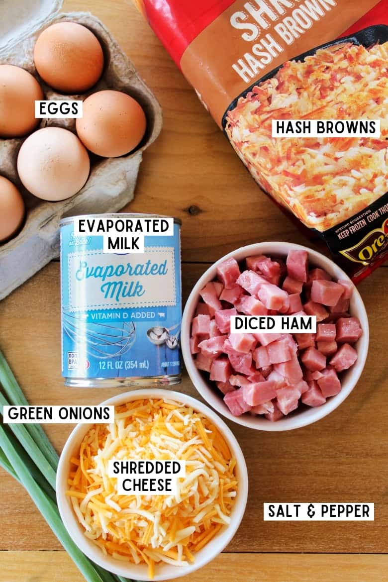 carton of eggs, can of evaporated milk, bowl of shredded cheese, bowl of diced cooked ham, bag of Ore Ida frozen hash browns, and green onions