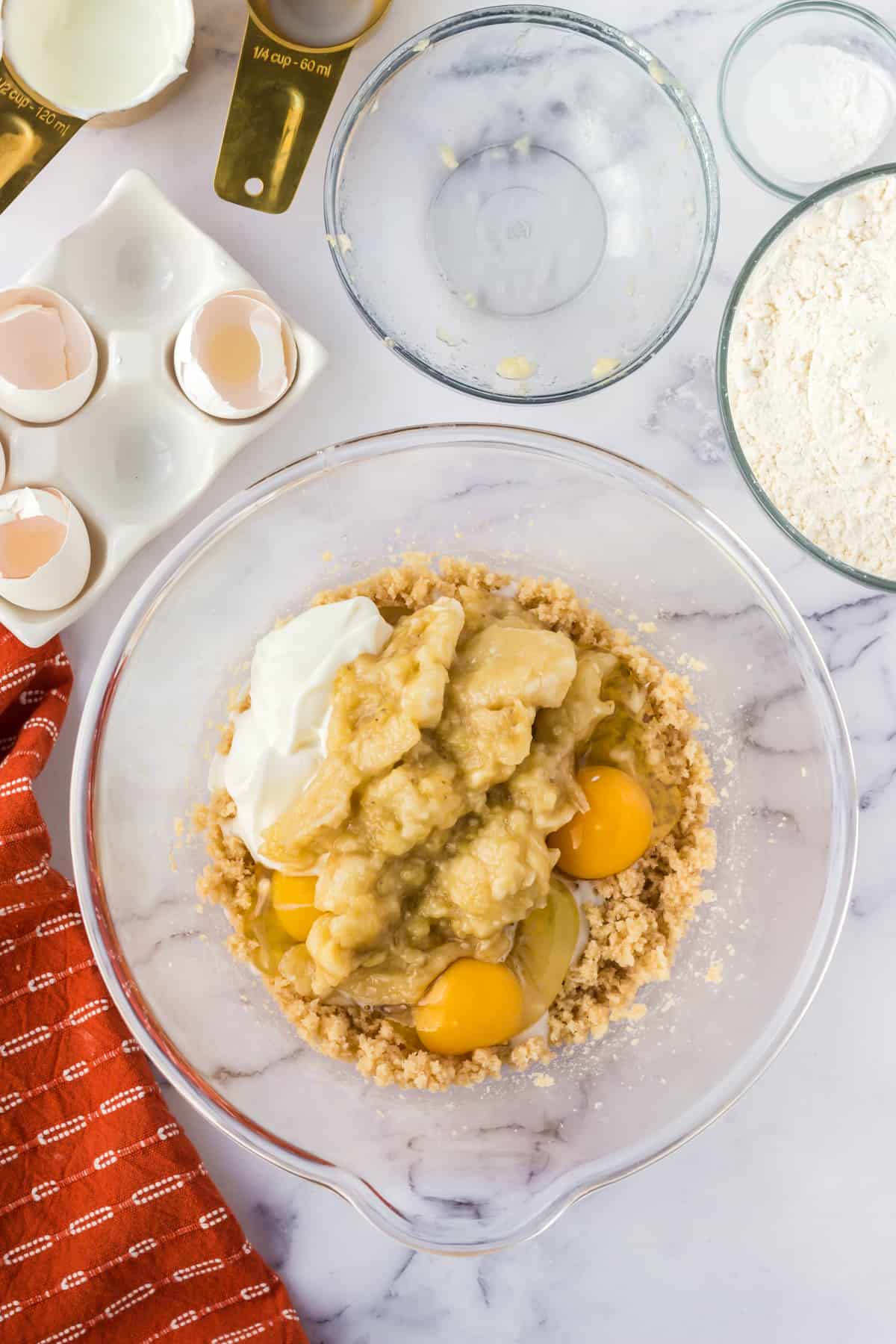 Greek yogurt, mashed bananas, and eggs added to the mixing bowl.