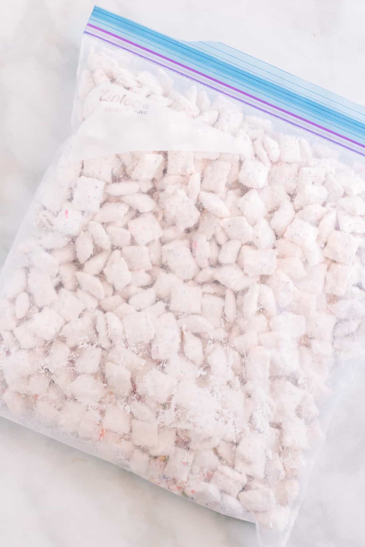 Large gallon size ziplock baggie filled with powdered sugar, funfetti mix, and white chocolate coated chex cereal
