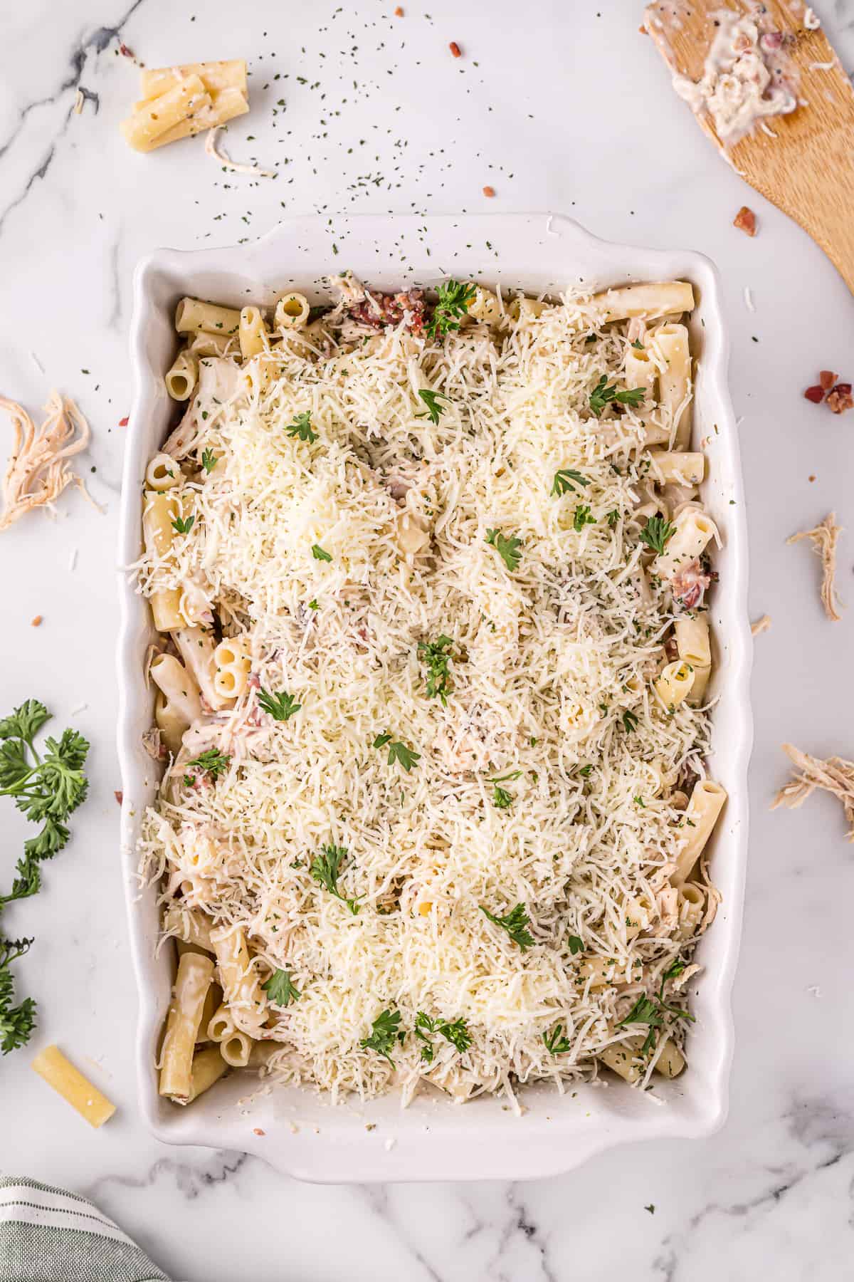 Unbaked chicken Alfredo casserole, topped with shredded cheese and parsley