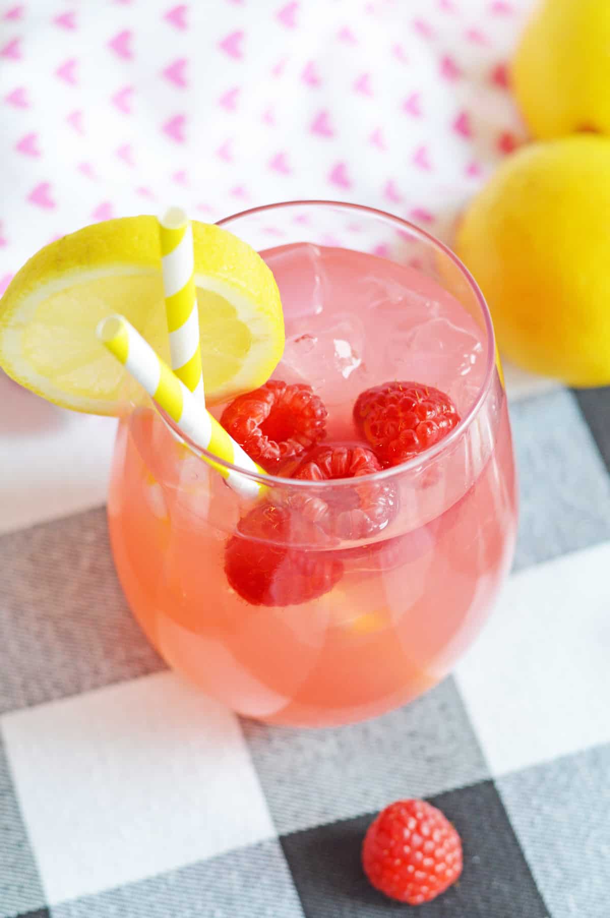 Raspberry lemonade cocktail made with vodka and garnished with fresh raspberries and a lemon slice.