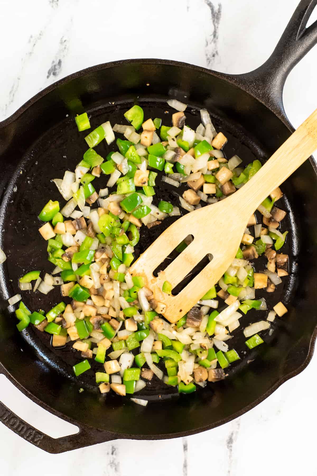 Chopped green peppers, onion, and mushrooms in skillet