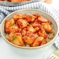 Sweet and spicy honey garlic chicken bites served over rice in a bowl.