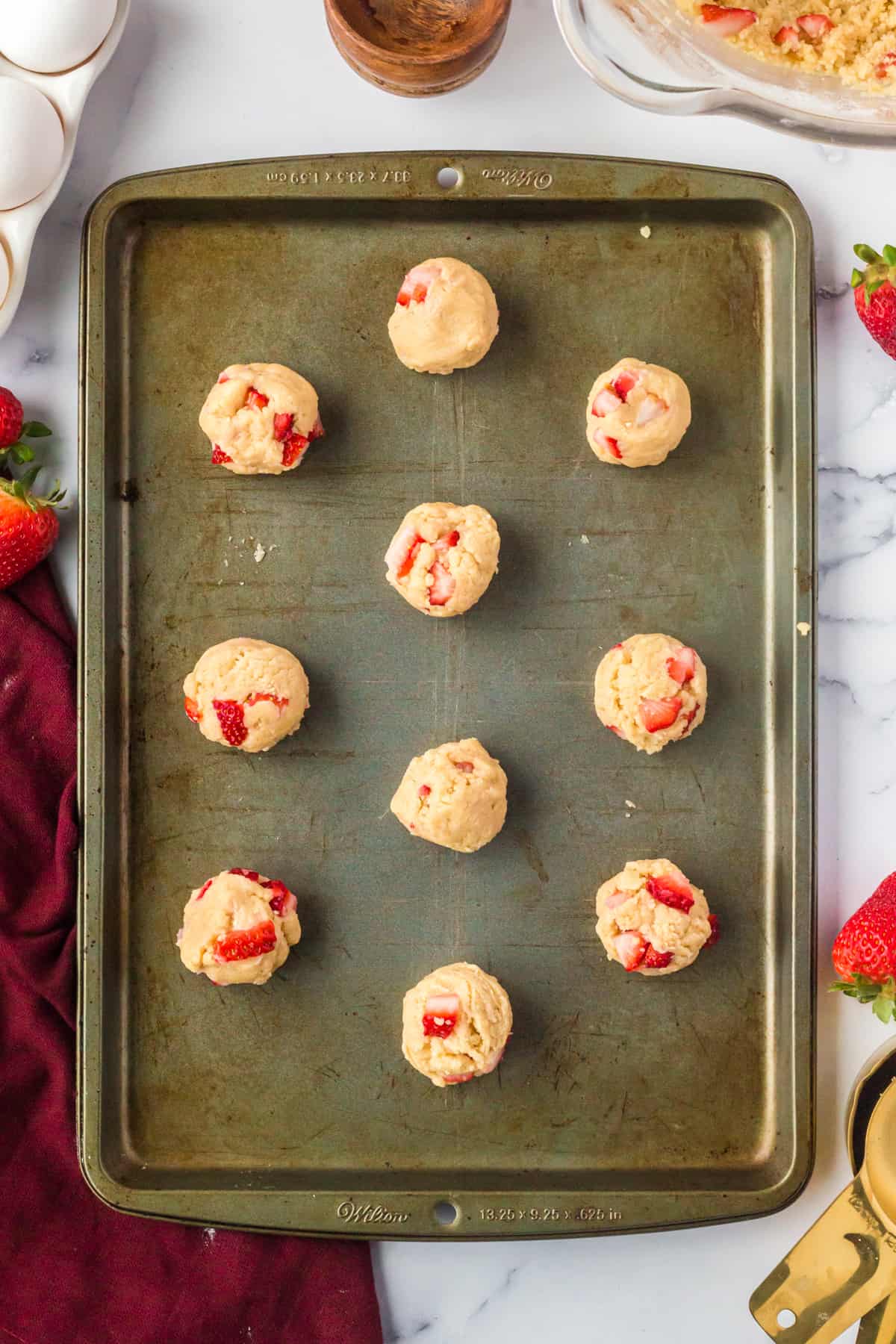 Unbaked cookies with fresh strawberries on baking sheet