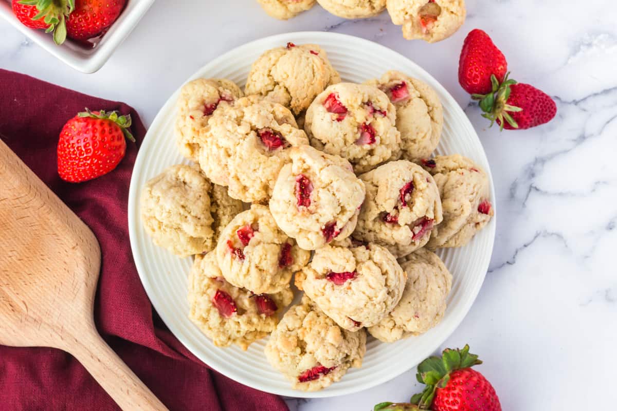 Strawberry Cookies piled on serving plate with fresh strawberries and more cookies around it