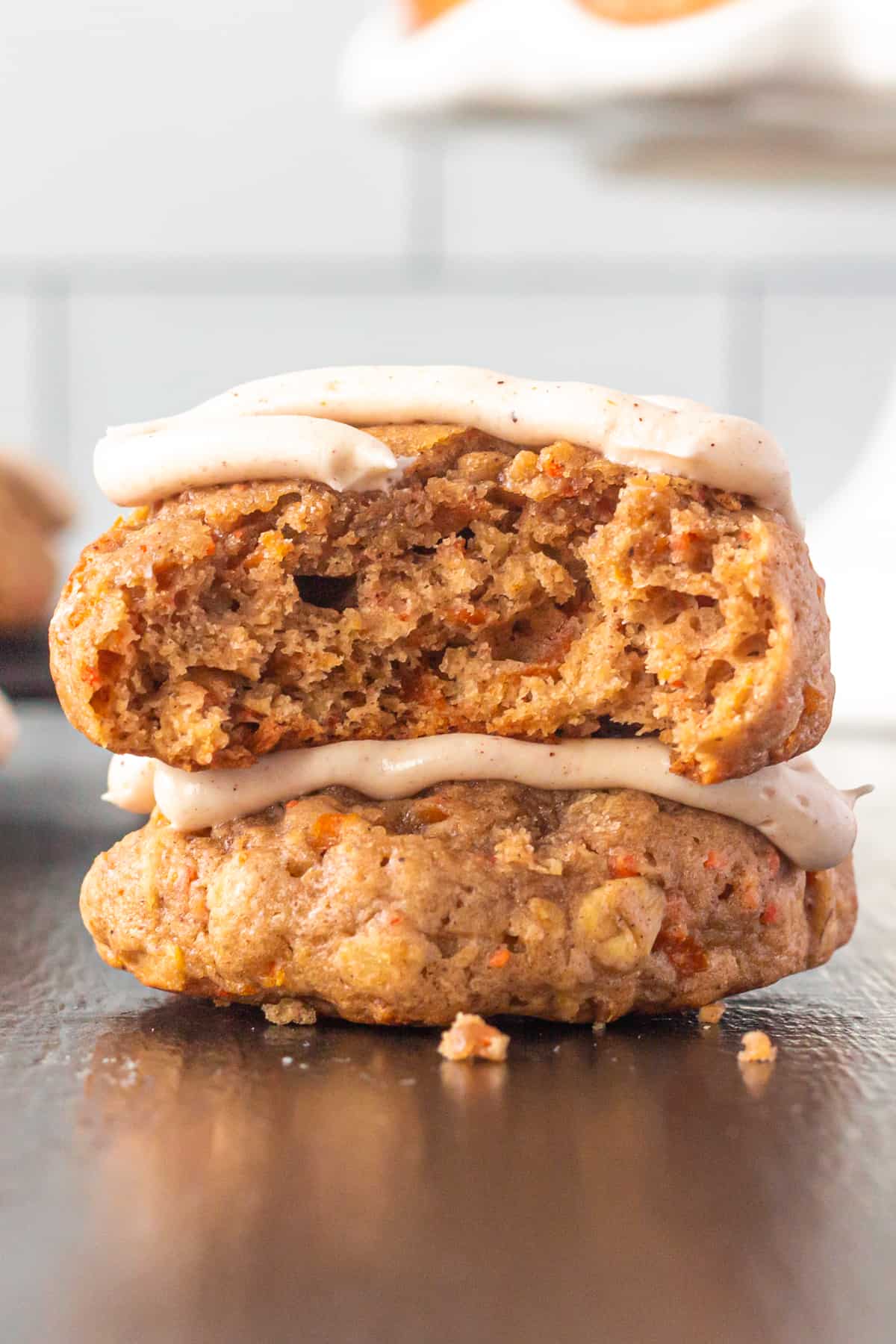 Thick and chewy carrot cake cookies with a bite taken out to show thick, chewy texture.