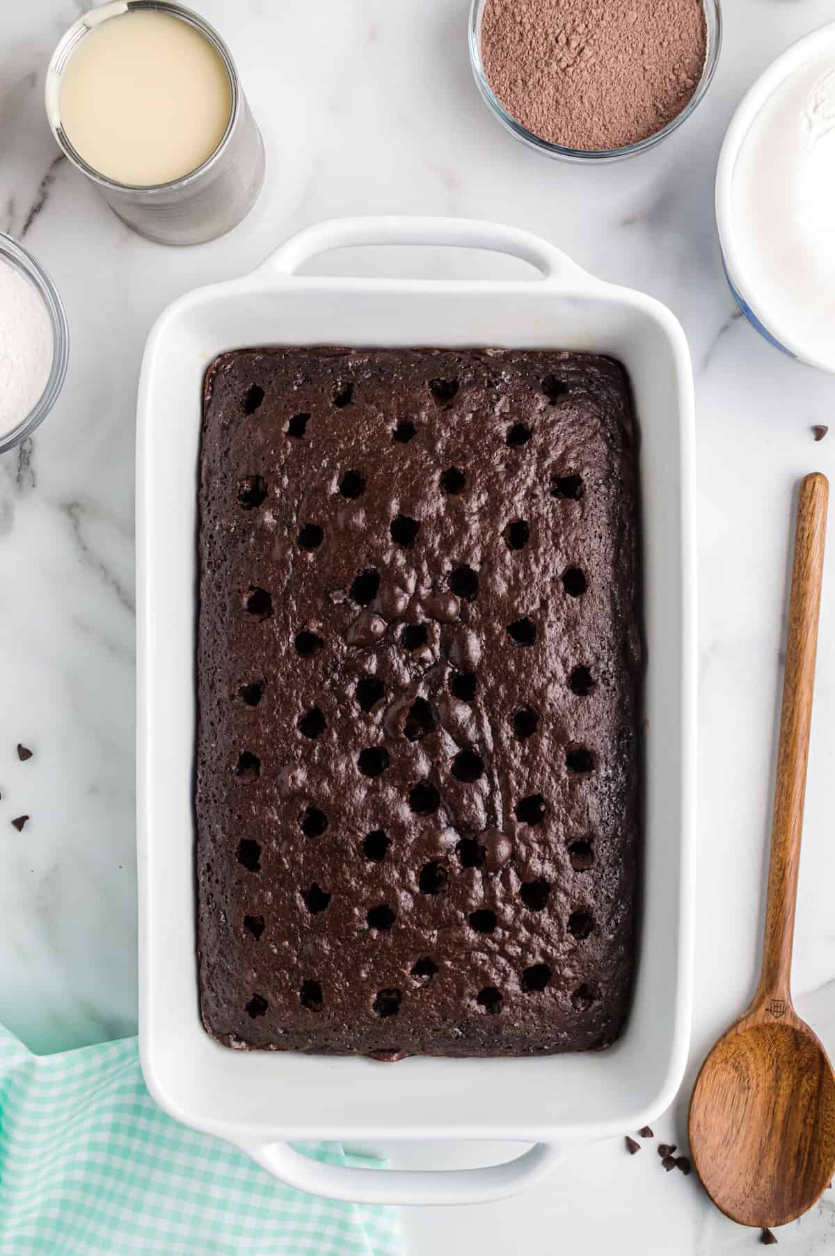 chocolate cake with holes poked in top with wooden spoon.