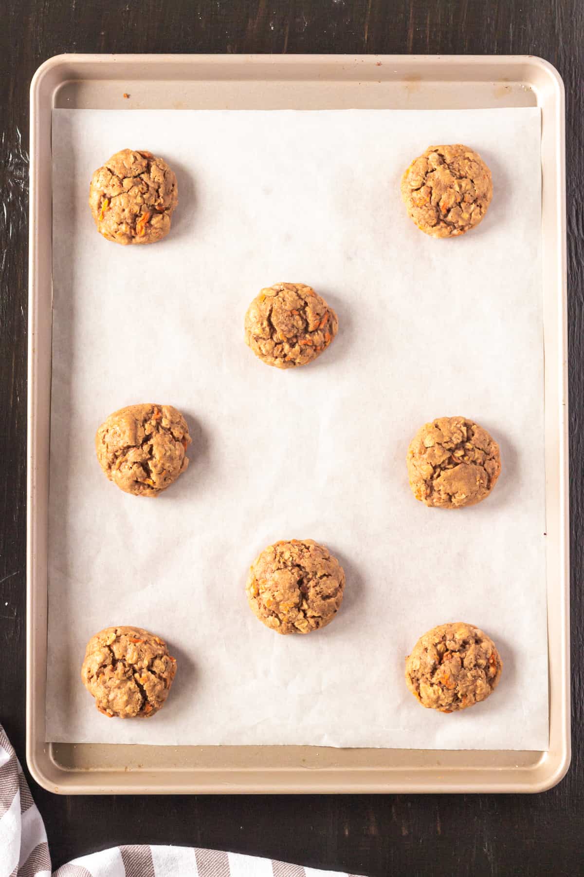 Homemade carrot cake cookies on lined baking sheet.