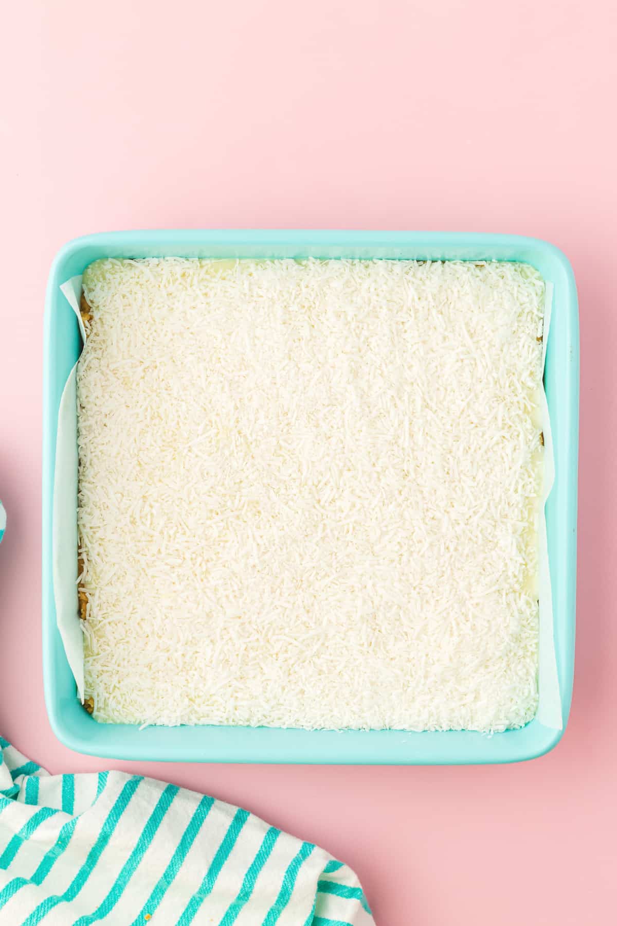 Shredded coconut in an even layer in square baking pan.