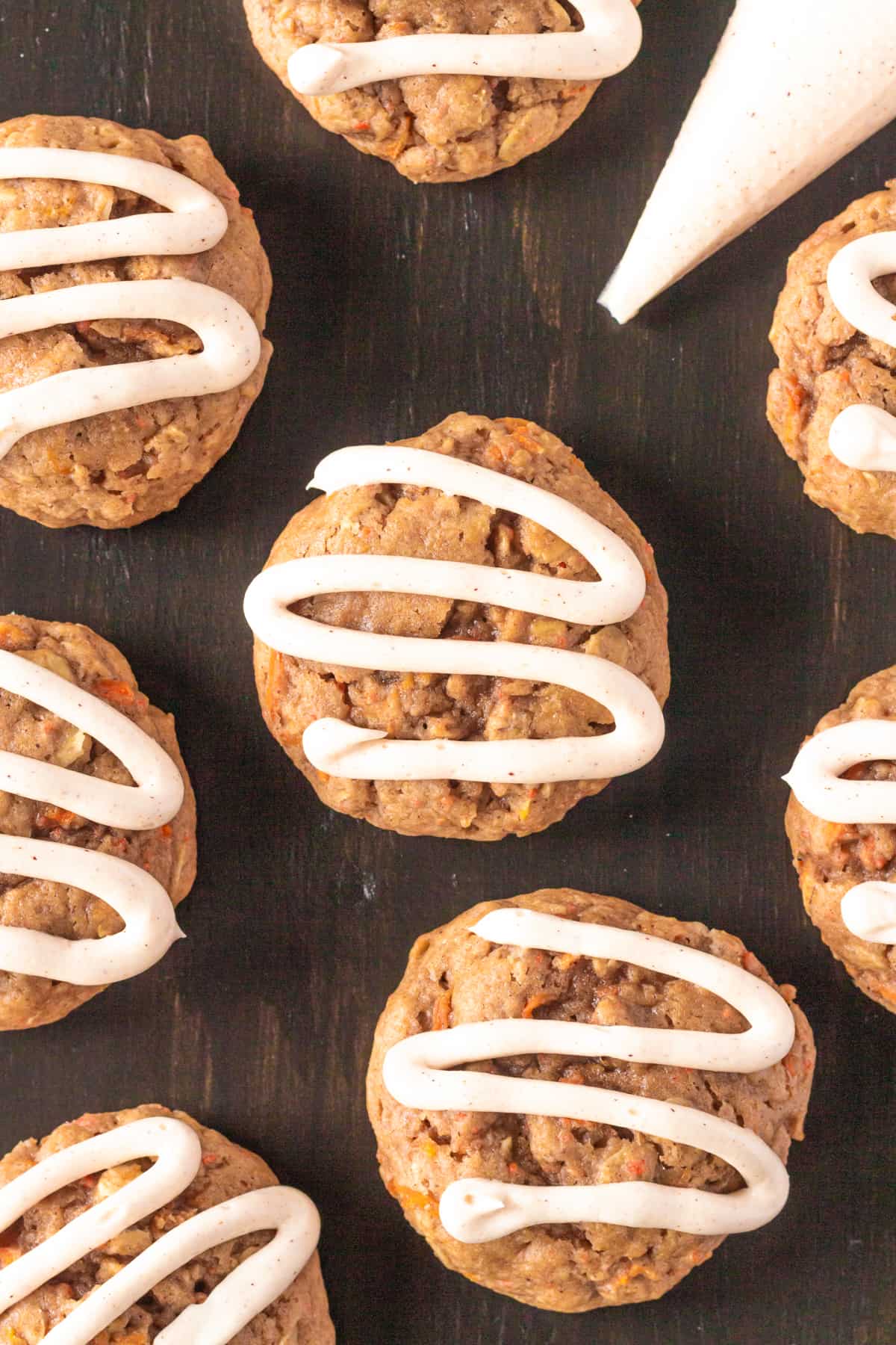Carrot cake mix cookies with frosting piped on top and piping bag next to them.