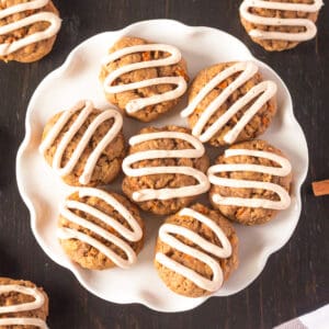 Carrot cake cookies with cream cheese frosting piped on top in zig zag pattern.