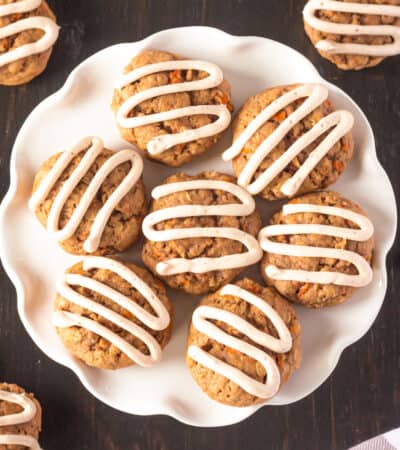 Carrot cake cookies with cream cheese frosting piped on top in zig zag pattern.