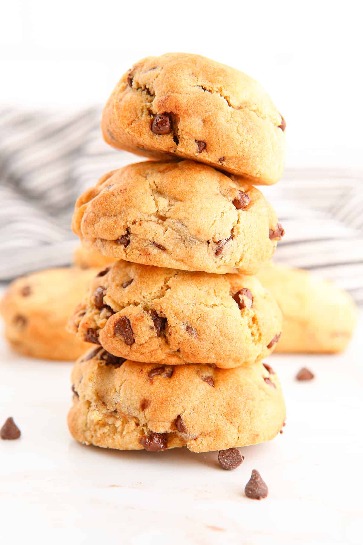 Thick air fryer chocolate chip cookies stacked on top of one another with more cookies in background.