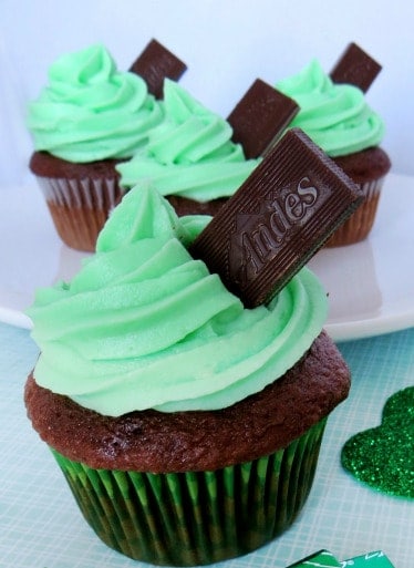 Chocolate cupcakes with mint frosting and andes mint candies sticking out of them.