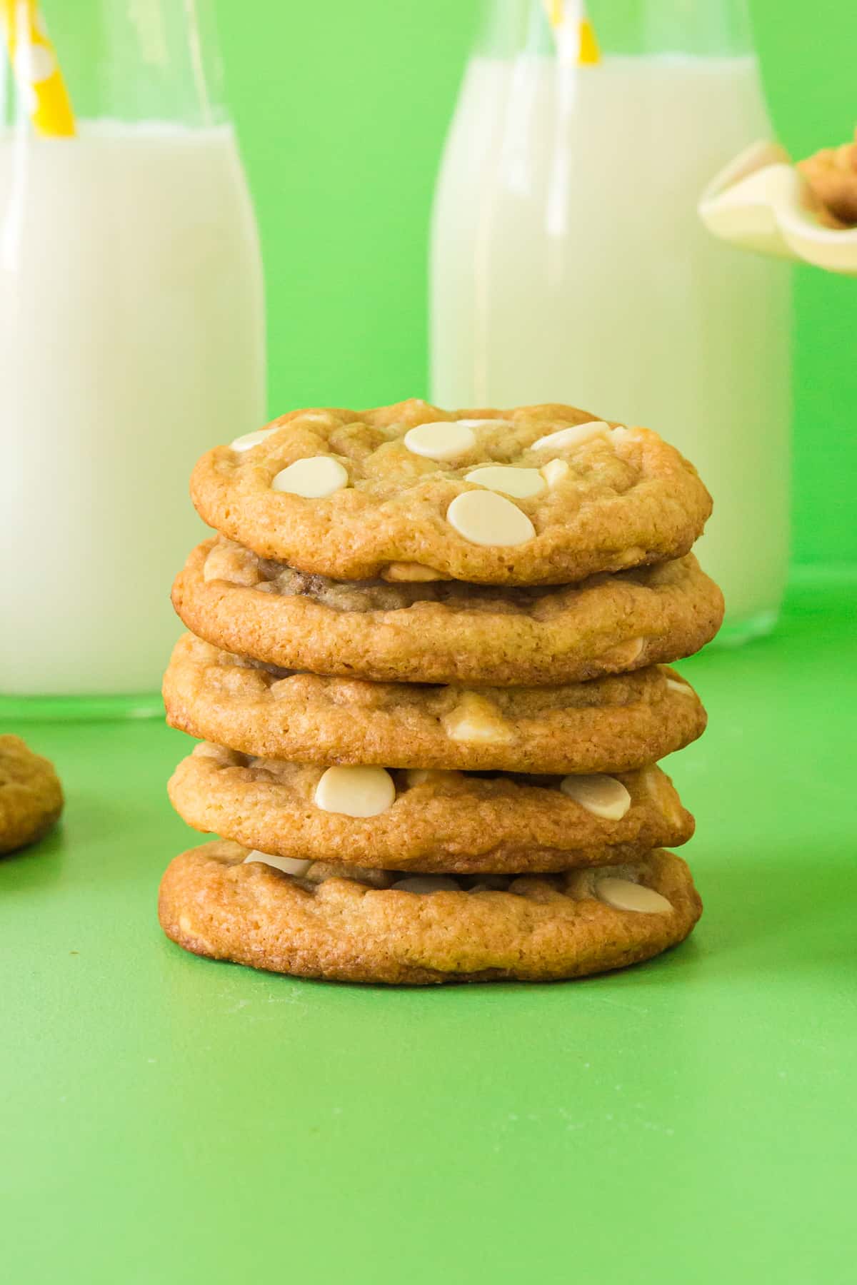 Chewy banana pudding cookies stacked on top of one another with milk in the background.