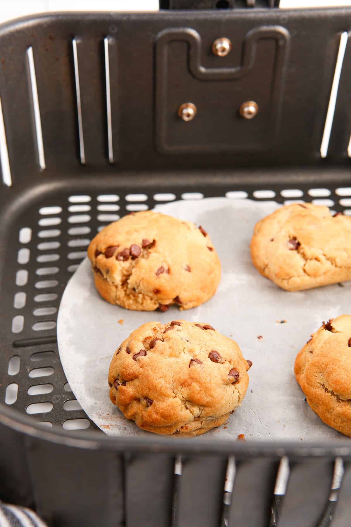 Chocolate chip cookies in air fryer basket.