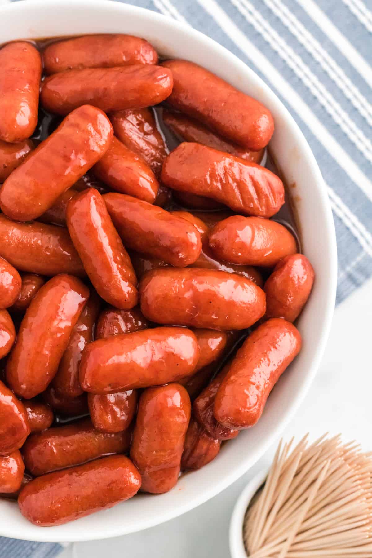 Crockpot BBQ Little Smokies in a white serving bowl with toothpicks.