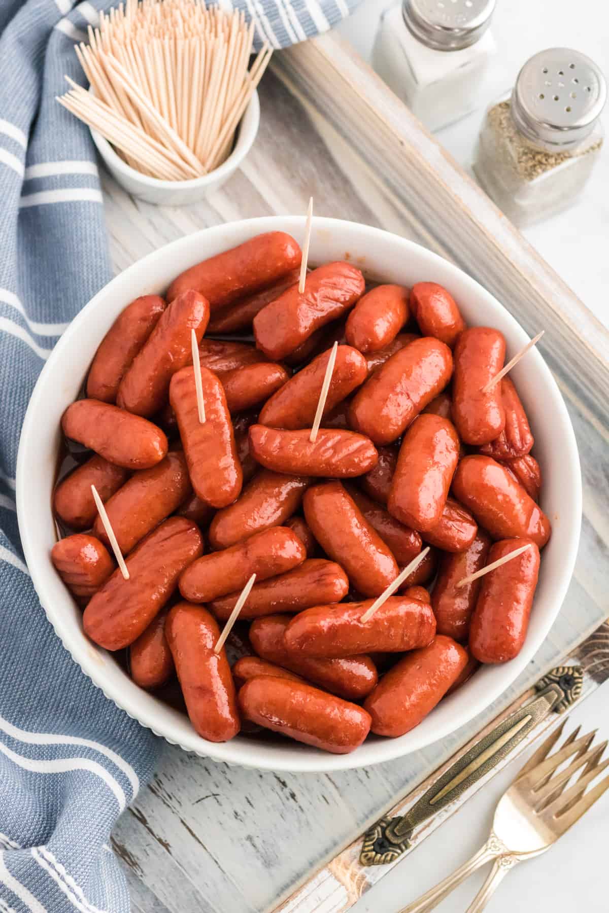 Crockpot little smokies in bbq grape jelly sauce served in a white bowl with toothpicks.