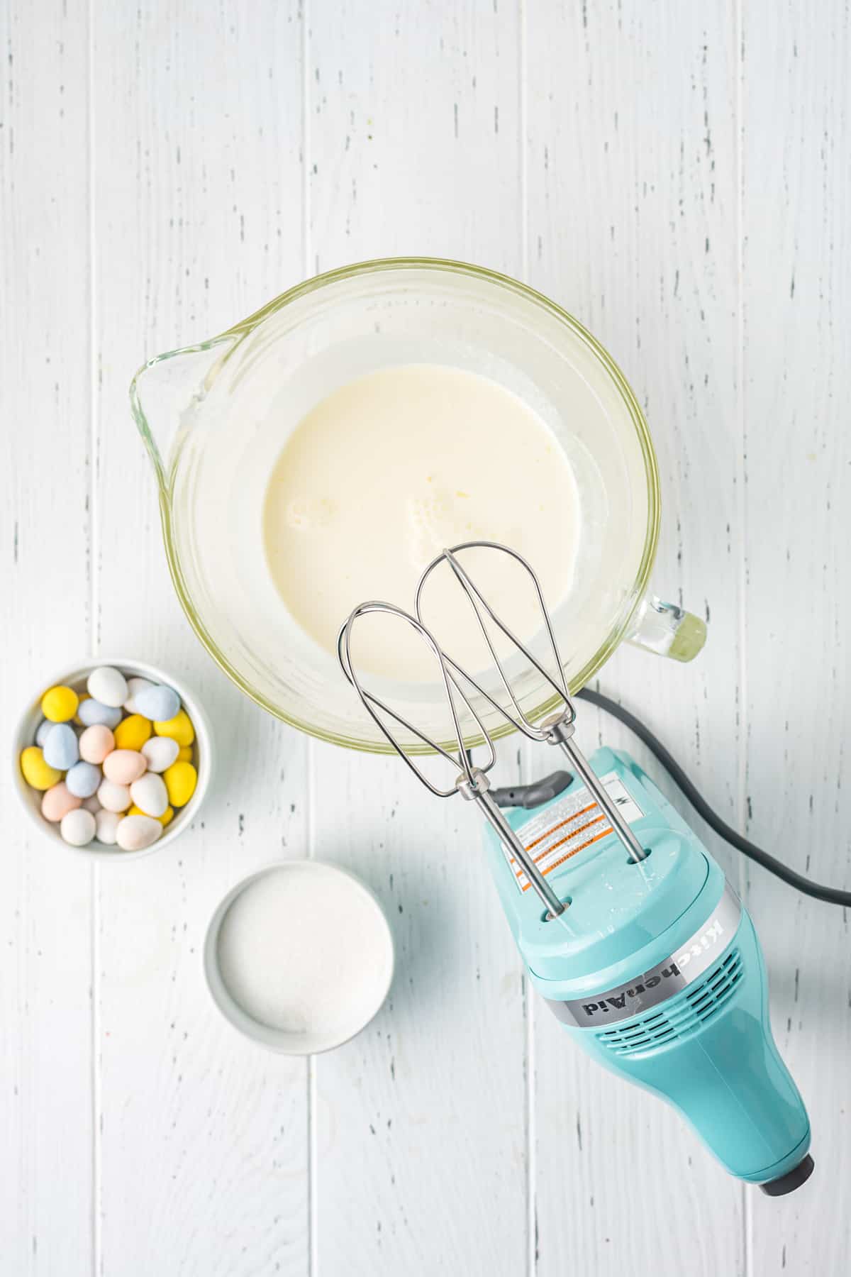 Making whipped cream filling in large glass mixing bowl with hand mixer.