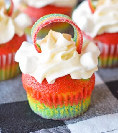 Rainbow Cupcakes with whipped cream cream cheese frosting and decorated with rainbow candy on top.