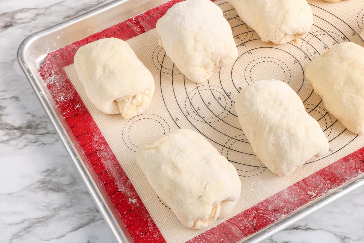 Unbaked rolls on lined baking sheet.