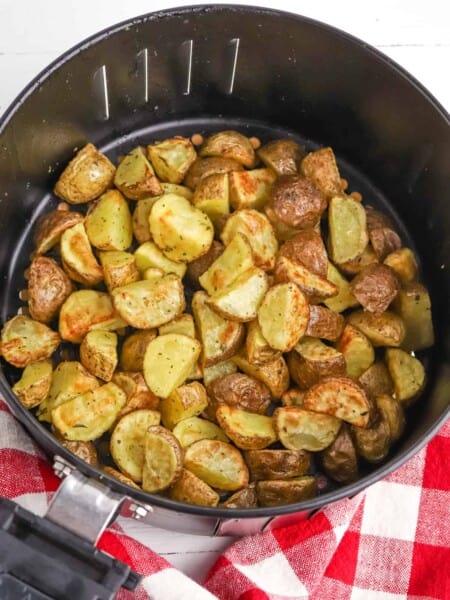 Seasoned, roasted potatoes in air fryer basket.