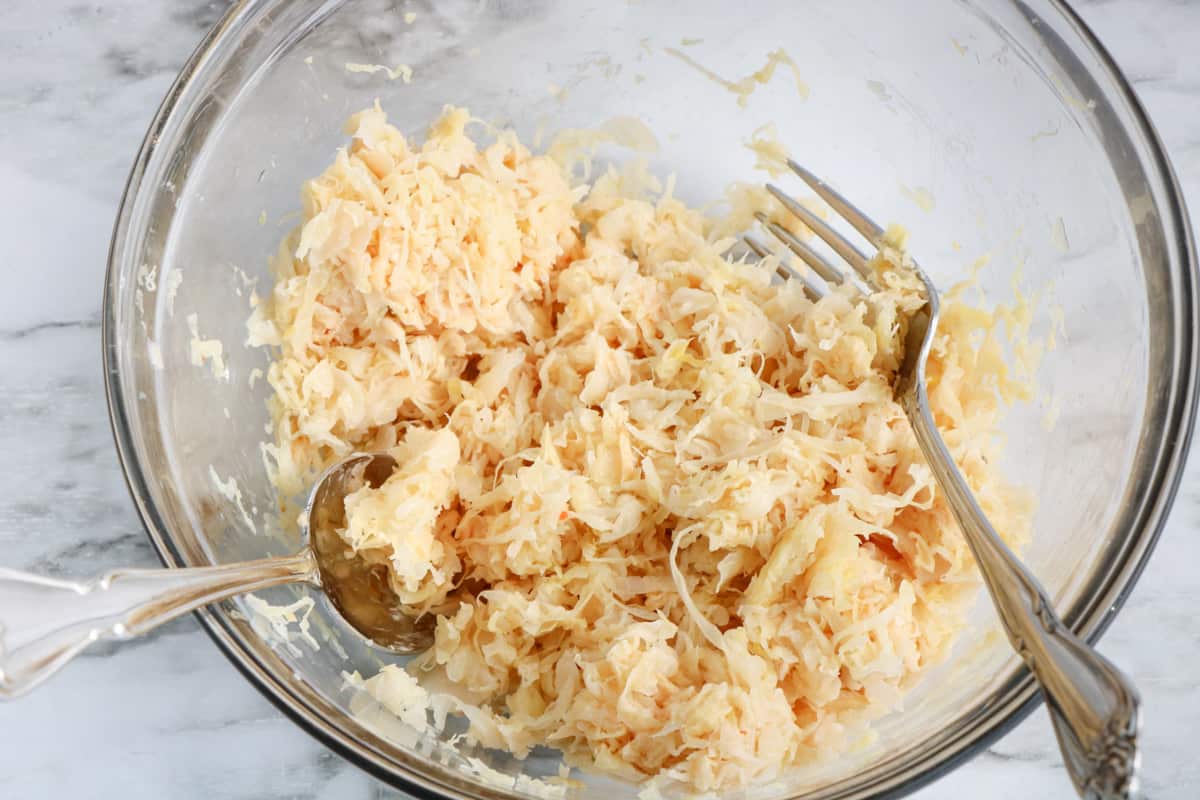 Sauerkraut and thousand Island dressing combined in a glass mixing bowl. 