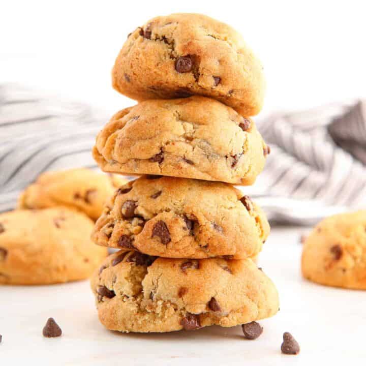 Air fryer chocolate chip cookies stacked on top of one another with more cookies in background.