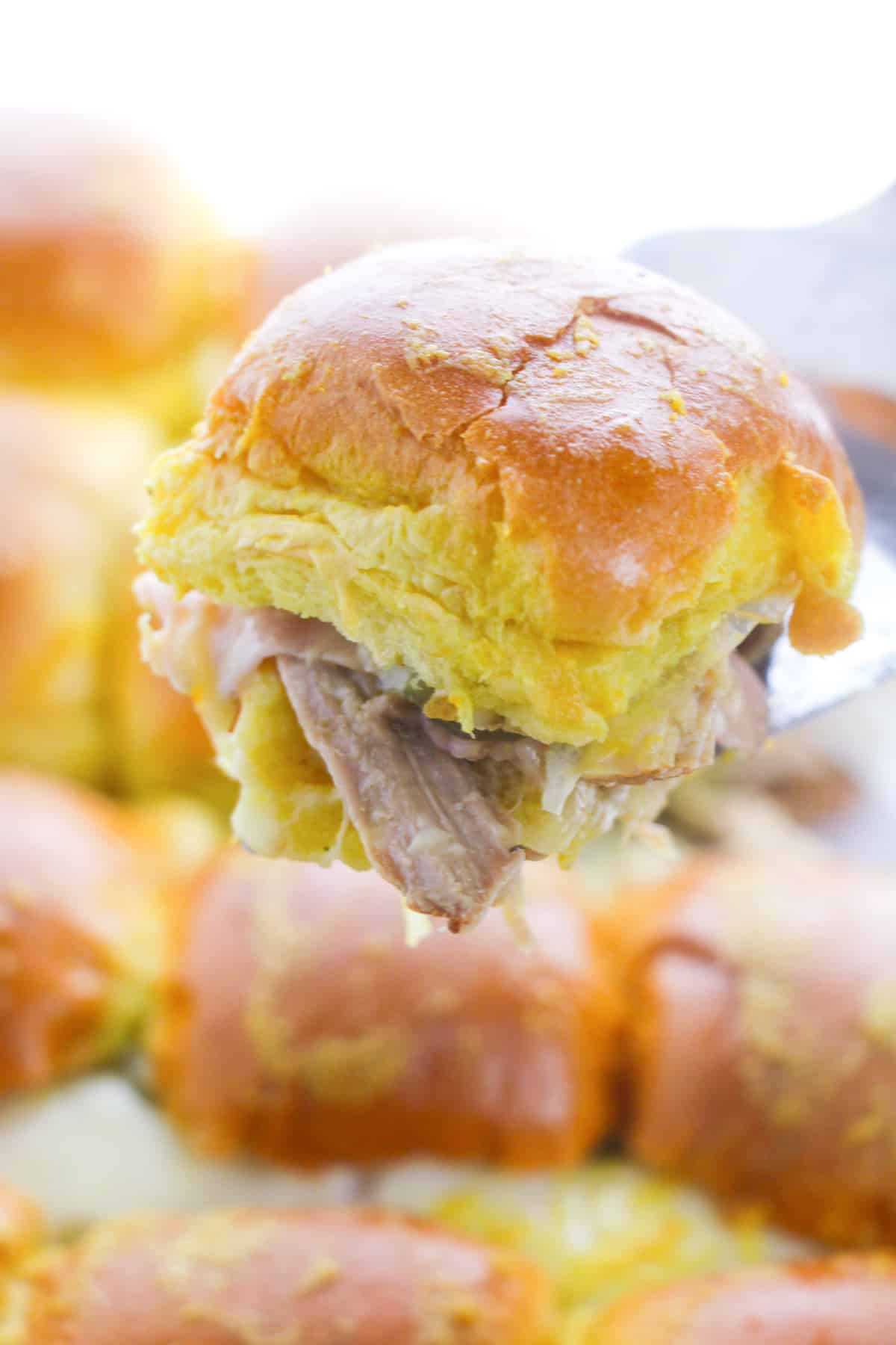 Spatula pulling a slider up out of baking dish.