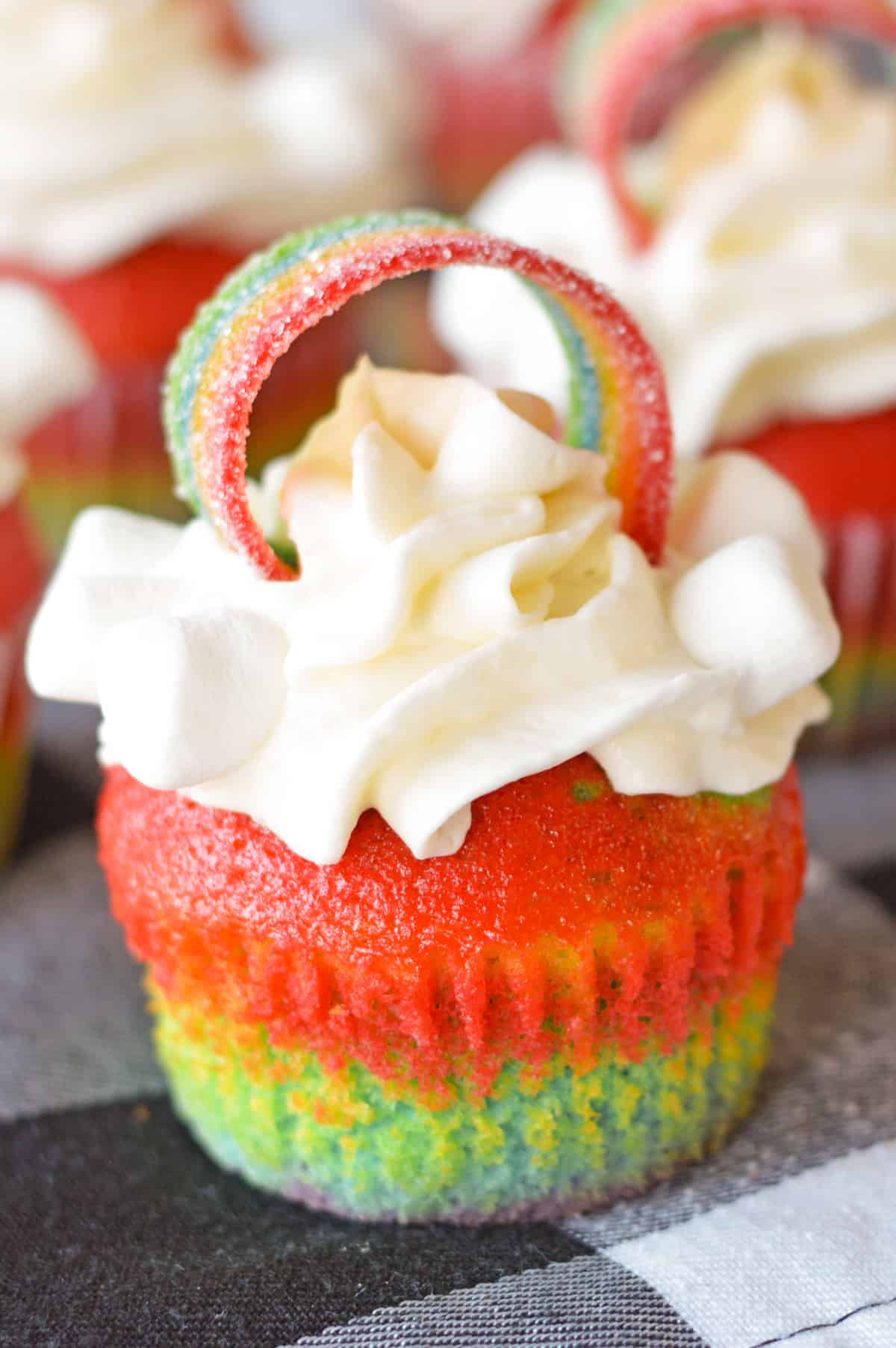 Rainbow Cupcakes with whipped cream cream cheese frosting and decorated with rainbow candy on top.