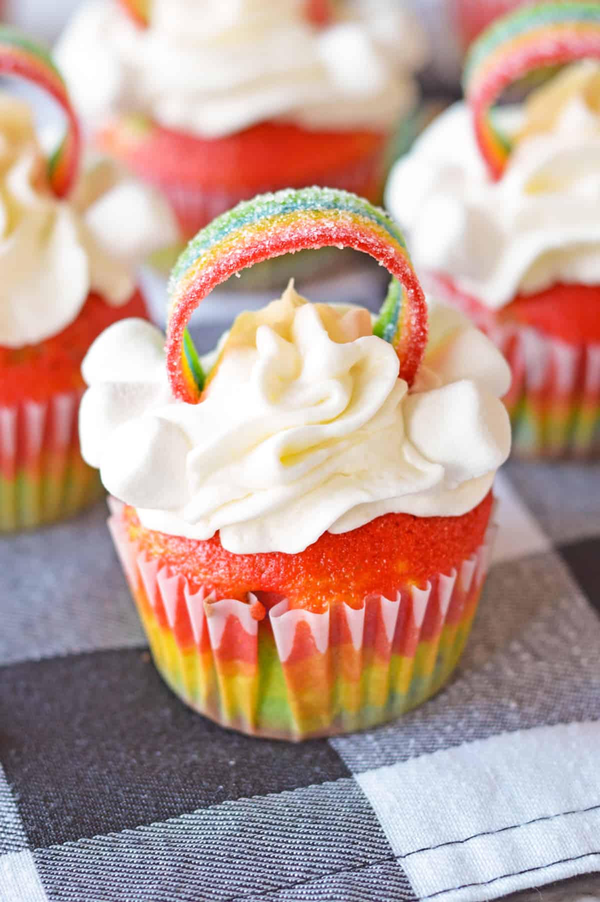 Cute Rainbow Cupcake with vanilla frosting piped on and rainbow airhead candy making an arch across the top.