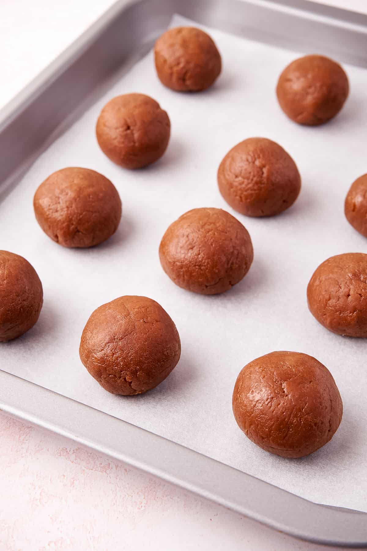 Rolled balls of biscoff cookie truffle mixture on lined baking sheet.