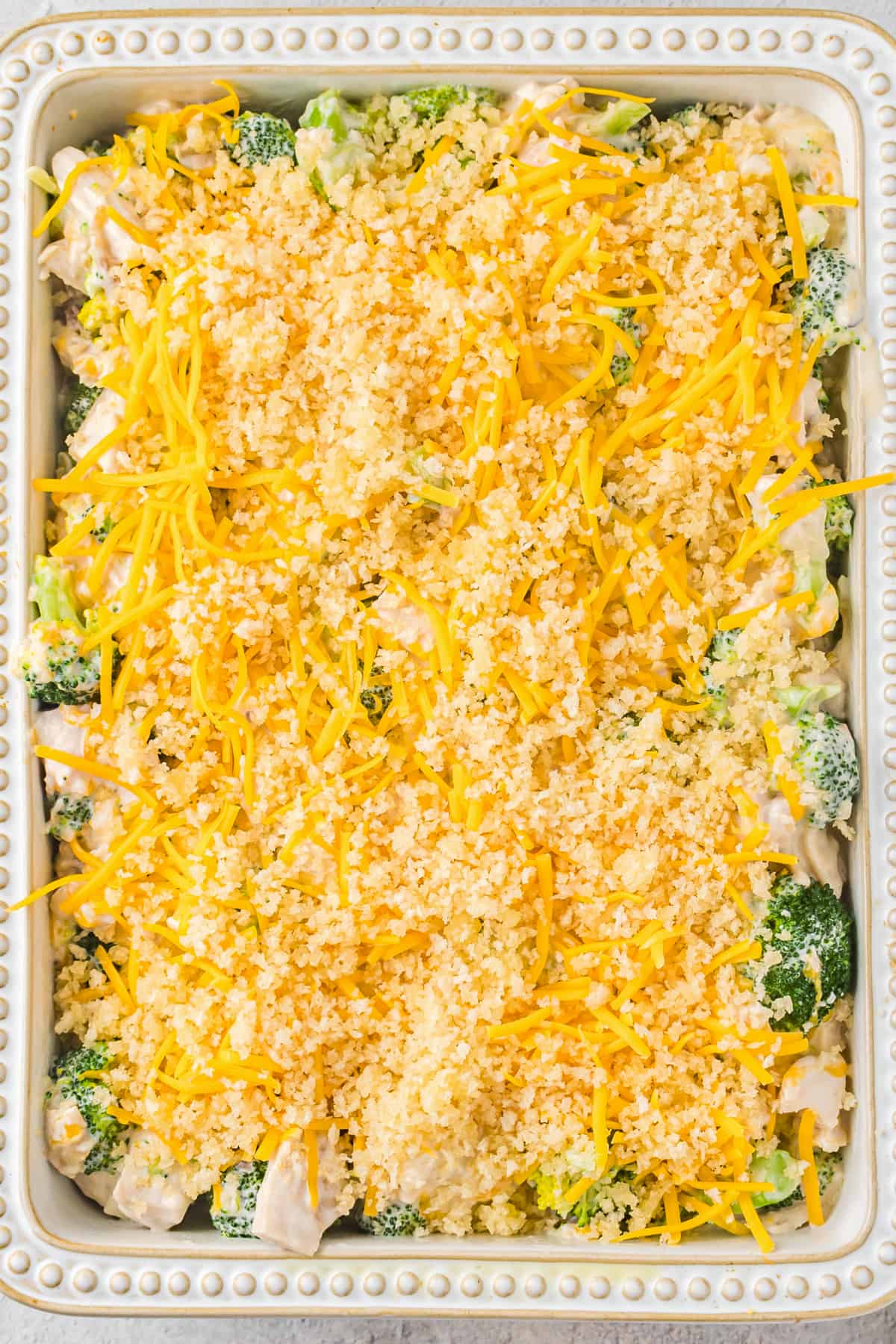 Chicken Divan topped with shredded cheese and panko breadcrumbs before baking.