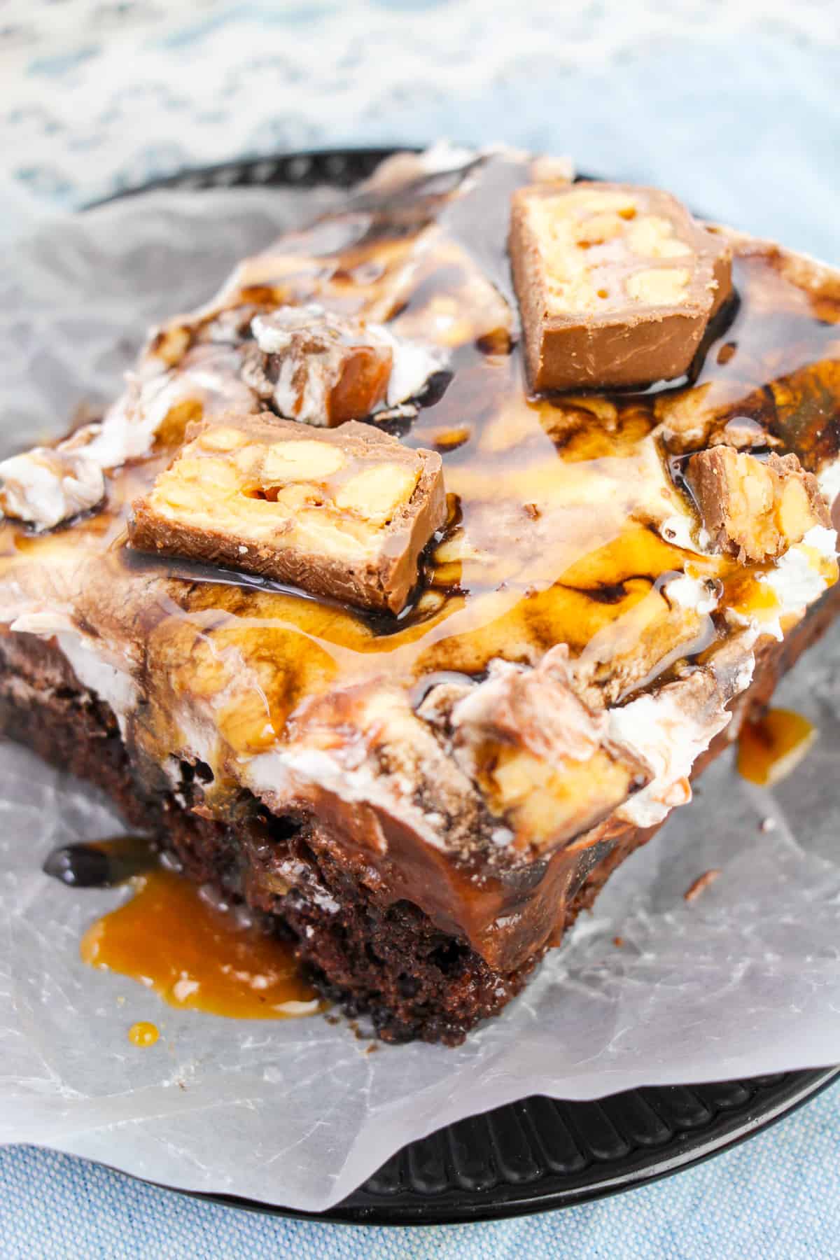 Snickers chocolate cake with whipped topping and chocolate and caramel sauces drizzled on top.