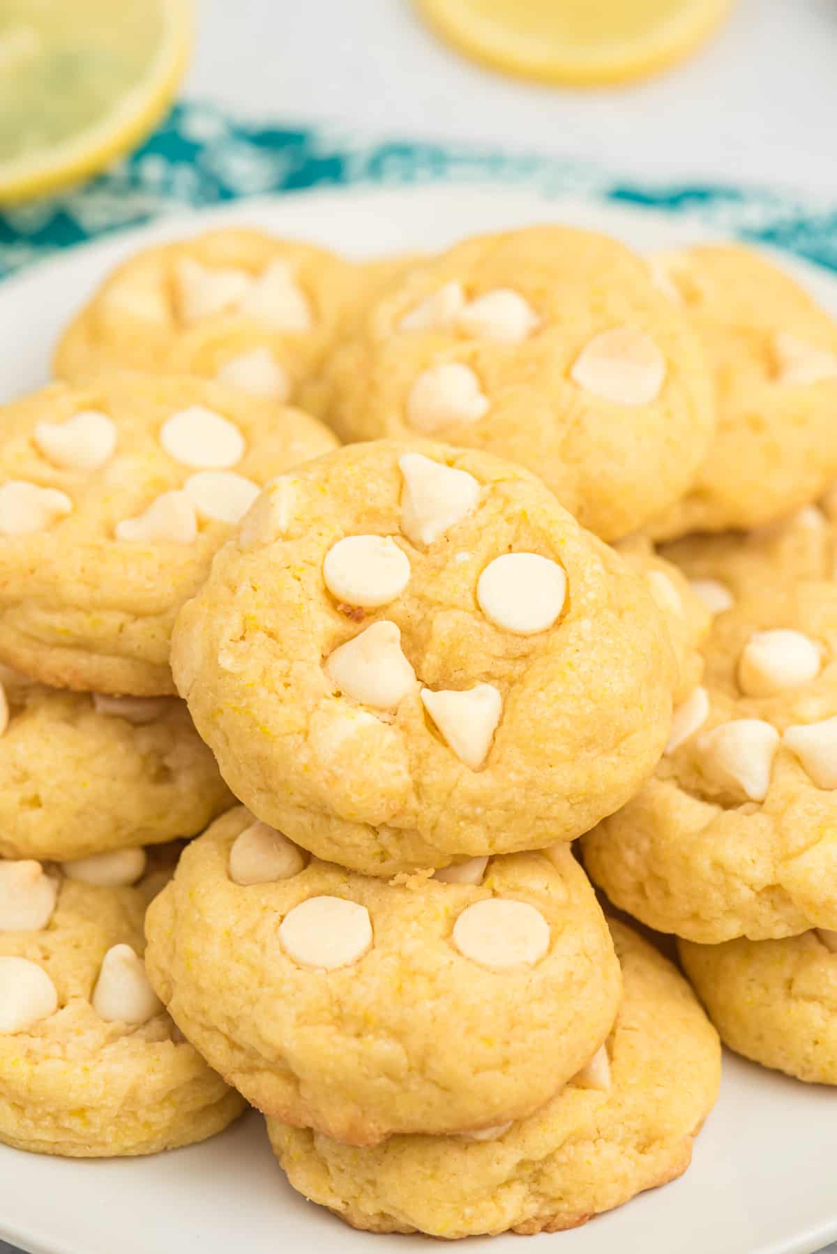Lemon pudding cookies with white chocolate chips piled on serving plate.