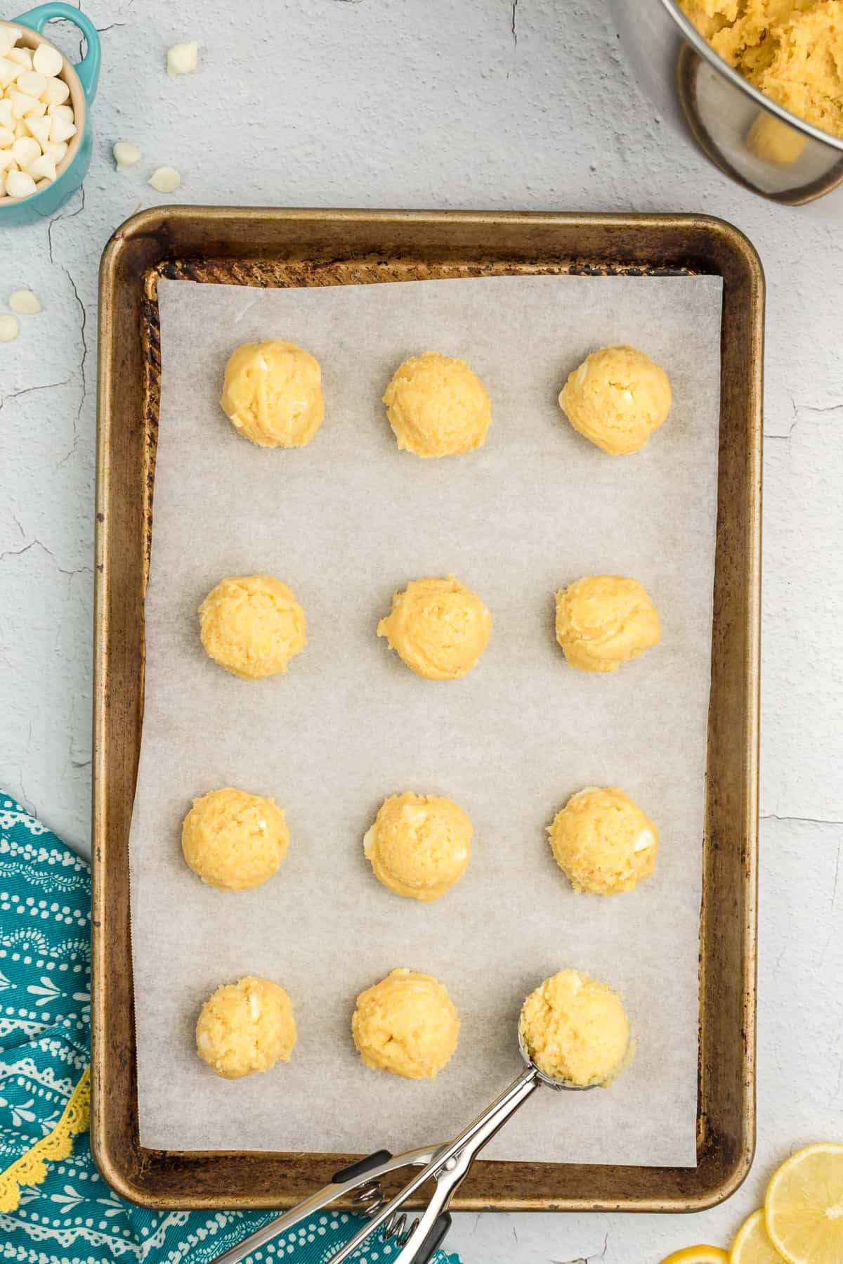 Lemon cookie dough scooped on lined baking sheet.
