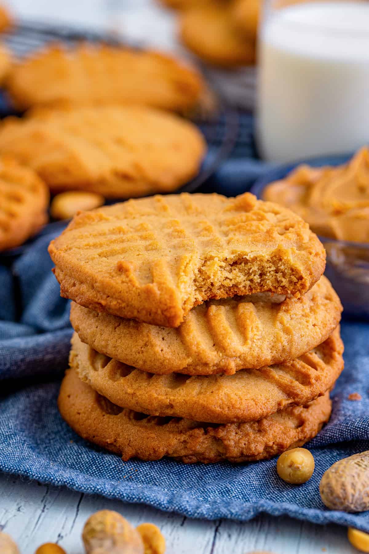 Old-fashioned peanut butter cookies with fork prong lattice on top. One cookie has a bite taken out of it to show crisp texture.