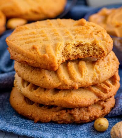 Old-fashioned peanut butter cookies with criss cross pattern on the top and bite taken out of one cookie.