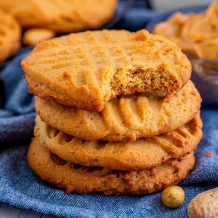 Old-fashioned peanut butter cookies with criss cross pattern on the top and bite taken out of one cookie.