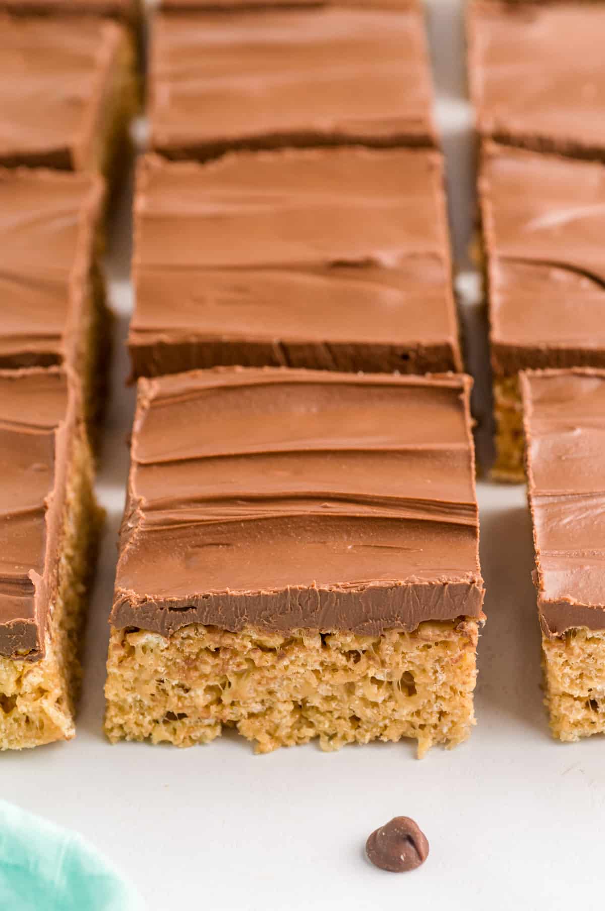 Peanut butter rice krispie treats with chocolate topping sliced and lined up neatly.