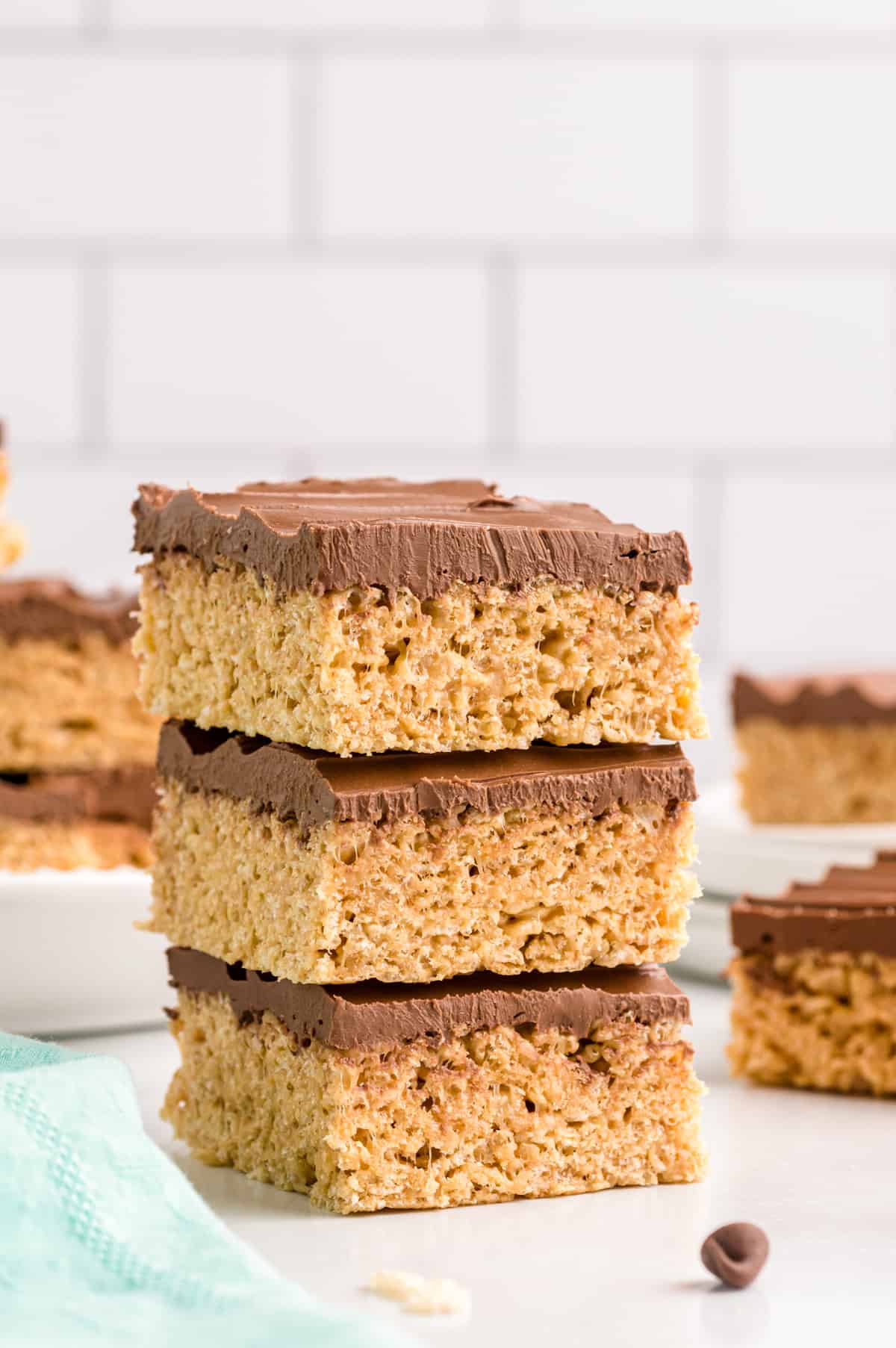 Peanut butter rice krispie treats with chocolate topping stacked three on top of each other.