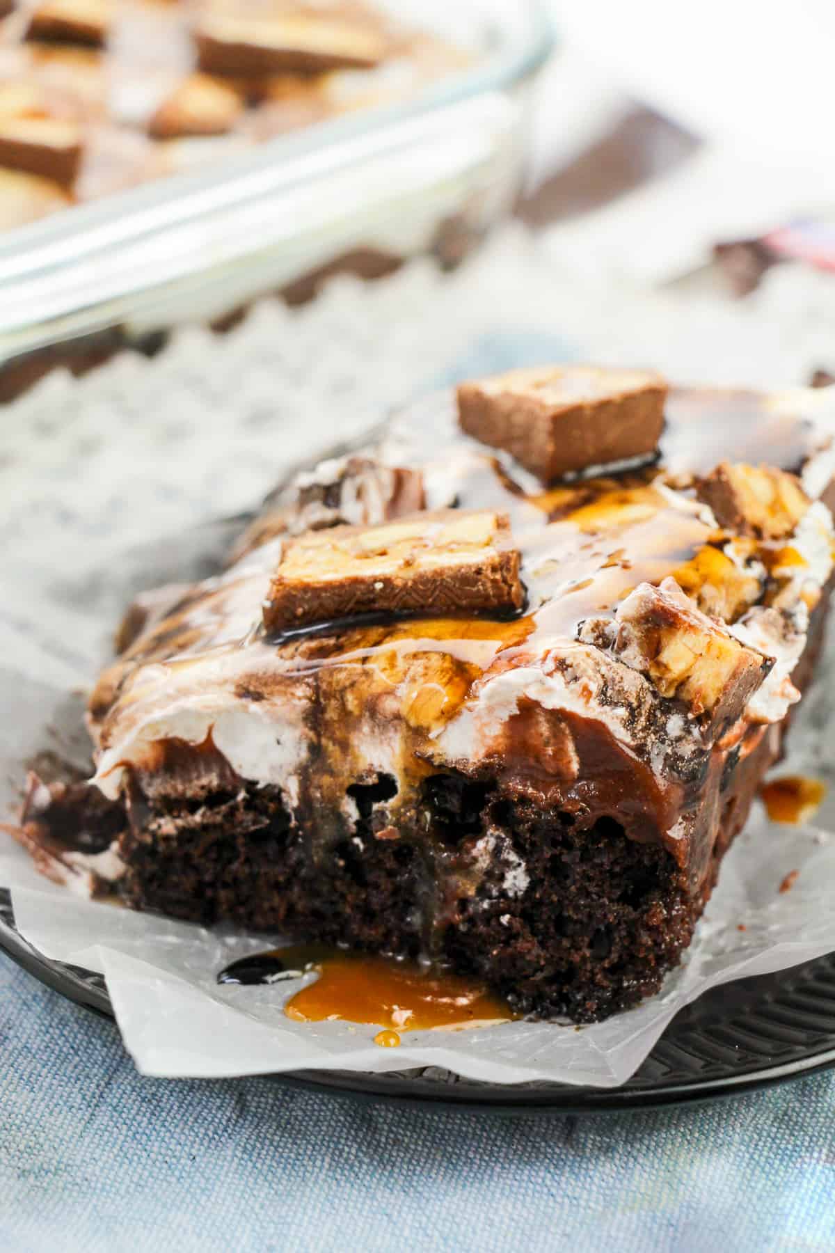 Chocolate snickers poke cake dripping with chocolate and caramel sauces.