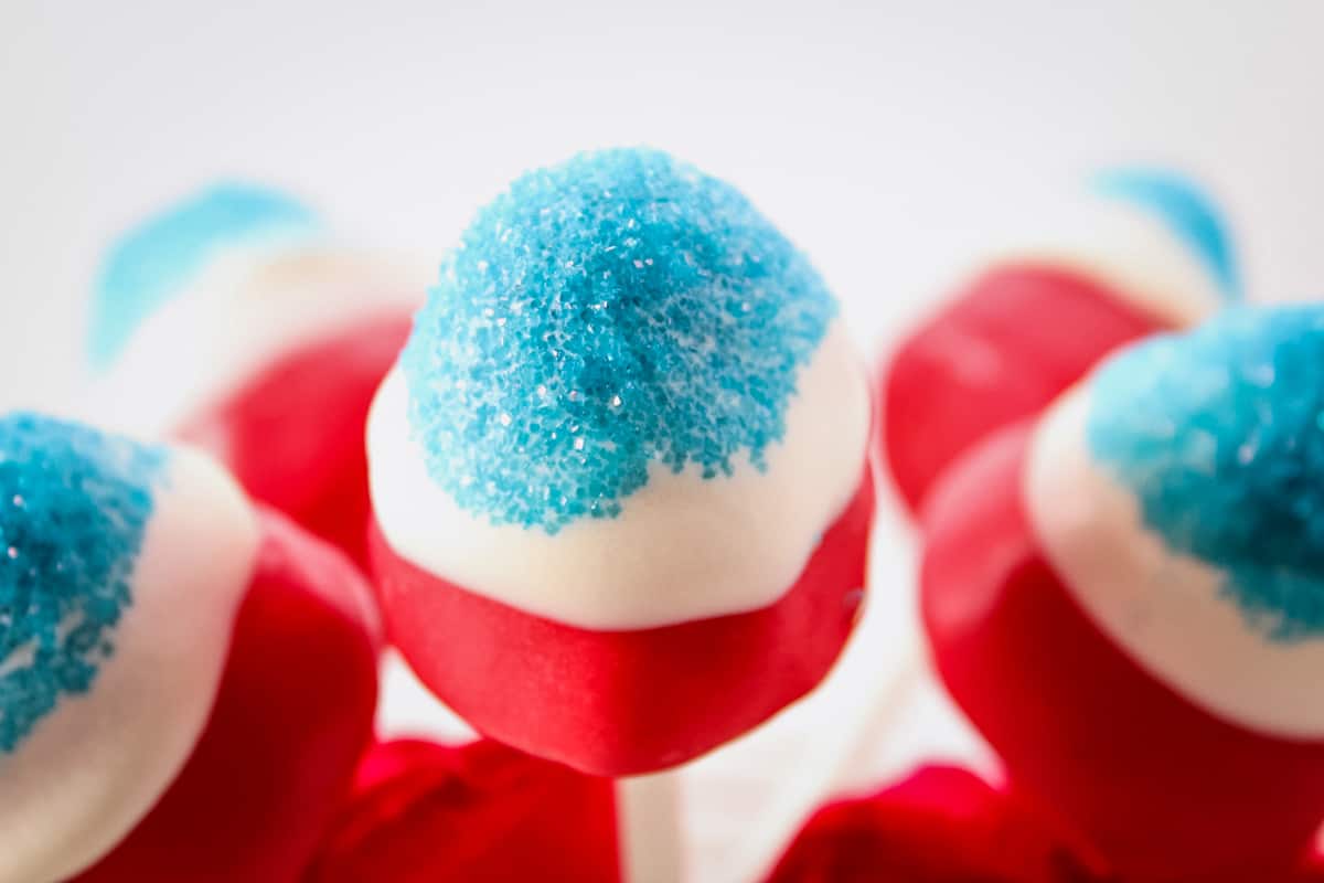 Close up of red and white candy coated strawberry with blue sanding sugar on the top.