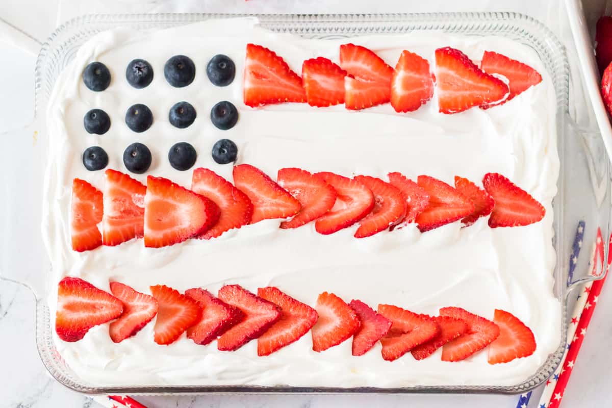 Sheet cake topped with sliced strawberries and blueberries to resemble a flag.