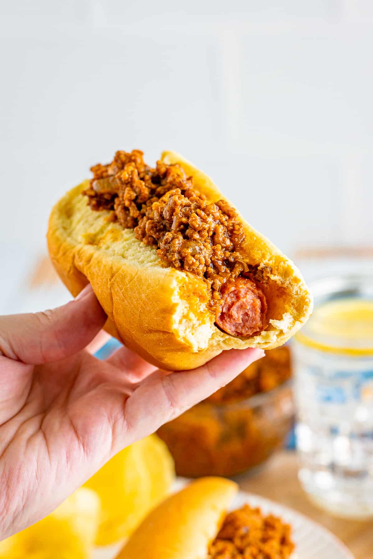 Chili topped hot dog with a bite taken out of it.