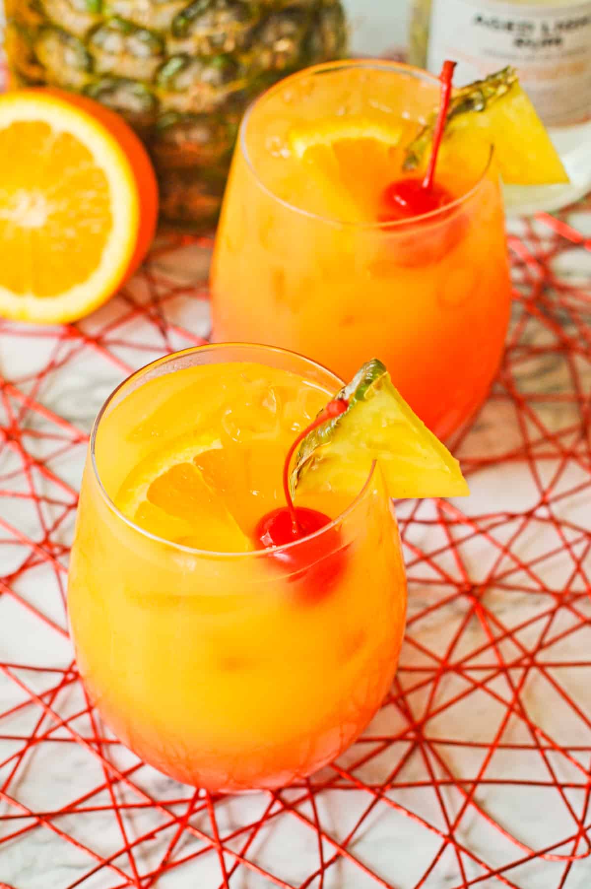 Rum Punch Cocktails with pineapple wedges, cherries, and orange slices.