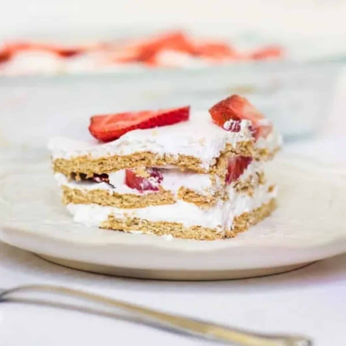 Slice of strawberry icebox cake made with layers of graham crackers, whipped topping, and fresh strawberries.