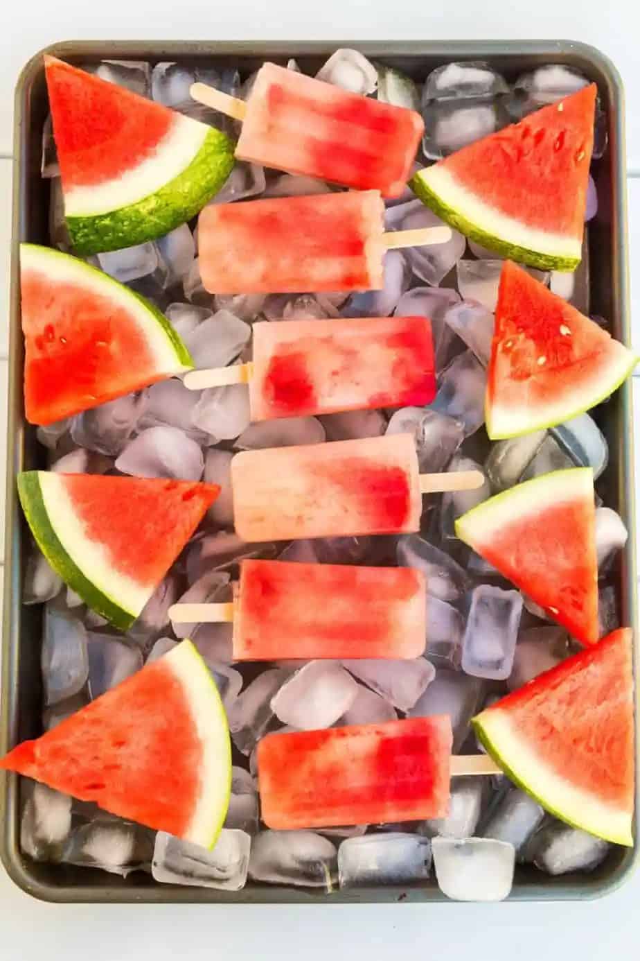 Watermelon popsicles on ice with fresh watermelon slices.