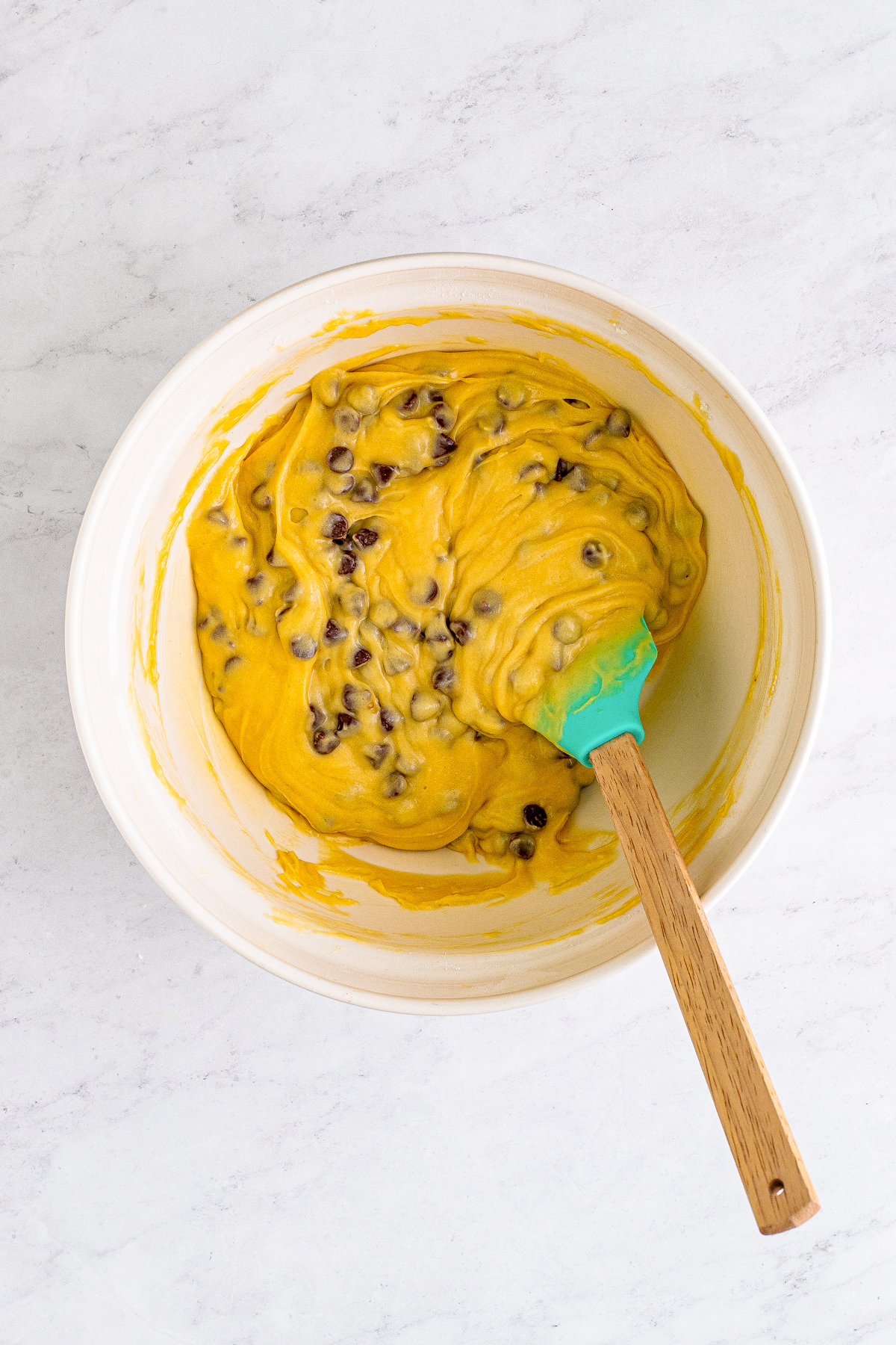 Chocolate chip muffin batter in mixing bowl with spoon.