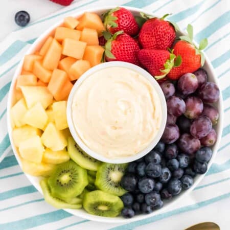 Cream cheese fruit dip on a platter surrounded by fresh fruit.